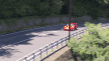a red car with a yellow stripe on the side is driving down a curvy road