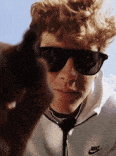 a man wearing sunglasses and a nike hoodie