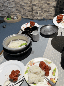 a table with plates of food including rice and chicken