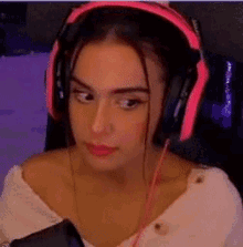 a woman wearing pink headphones is sitting in a chair and looking at the camera .
