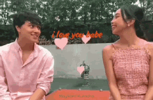 a man and a woman are sitting next to each other in a park and smiling at each other .