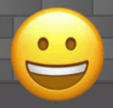 a close up of a smiley face with a big smile and a brick wall in the background .