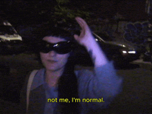 a woman wearing sunglasses says " not me i 'm normal " in yellow letters