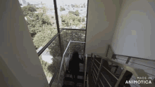 a person is walking down a set of stairs with a view of a city and trees .