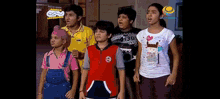 a group of children are standing next to each other in front of a sign that says ' infinity ' on it .