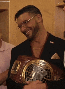 a man in a suit holds a world heavyweight wrestling belt