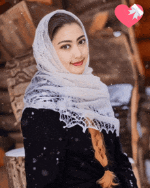 a woman wearing a white scarf and a black coat with a heart behind her