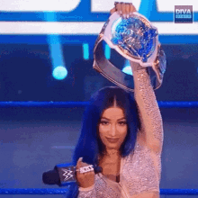 a woman with blue hair is holding a wrestling championship belt in her hand .
