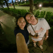 two women posing for a picture with one wearing a white shirt that says ' i love you ' on it