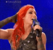 a woman with red hair is holding a microphone with a w logo on it