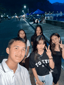 a group of people posing for a picture one of them wearing a tokyo shirt