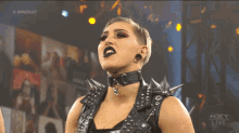 a woman wearing a choker with spikes on it stands in front of a screen that says #wwe nxt