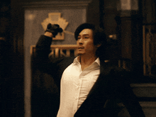 a man in a suit and white shirt is holding a knife in his right hand