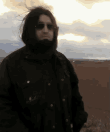 a man with a beard wearing sunglasses and a black jacket