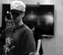 a man wearing a hat and sunglasses is standing in front of a blackboard in a black and white photo .