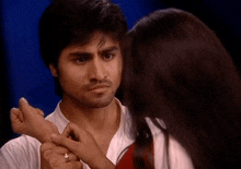 a man and a woman are looking at each other and the woman is touching the man 's arm
