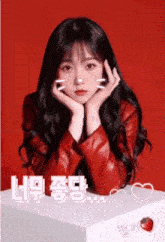 a girl in a red jacket is sitting on a white box with a strawberry in the background