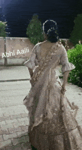 a woman in a white dress is standing in front of a sign that says abhi aaiii