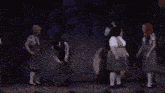a group of young girls are holding hands on a stage .