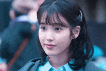 a close up of a woman wearing a blue shirt and a grey jacket