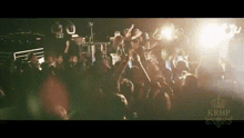 a crowd of people are gathered in a dark room with the word krof on the bottom