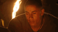 a man is sitting in front of a fire and looking at it .