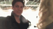 a man and a woman are standing next to each other in a room and talking to each other .
