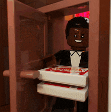 a lego man in a tuxedo is carrying a box of pizza