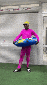 a man in a pink outfit is holding a blue inflatable tube in front of a nutella store