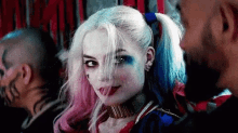 a woman in a harley quinn costume is looking at a man in a crowd .