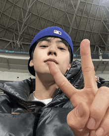 a man wearing a blue hat and a black jacket is giving the peace sign