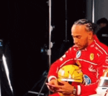 a man in a red jacket is holding a yellow helmet and looking at his phone .