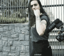 a woman is holding a rode camera on her back