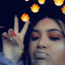 a woman is making a peace sign with her hand in front of a fire .