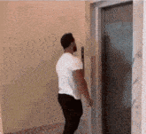 a man in a white shirt is standing in front of an elevator door .