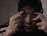 a man with headphones on holds his eyes open