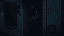 a woman is standing in a dark room with a mirror on the wall