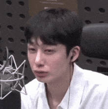 a young man wearing headphones is sitting in front of a microphone and crying .