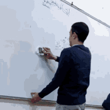 a man is cleaning a white board with arabic writing on it