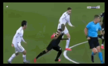 a group of soccer players are playing on a field with a referee in the background