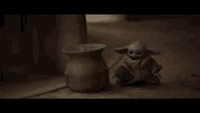 a baby yoda figurine sits next to a pot