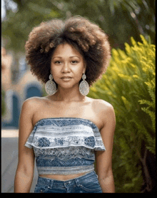 a woman wearing a strapless top and earrings
