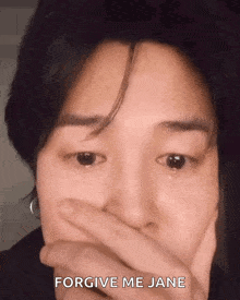 a close up of a person covering their mouth with their hand and a tear is coming out of their eye .
