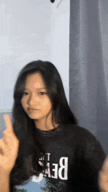 a girl with long black hair is wearing a black shirt that says ' beef ' on it .