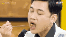 a young man is eating food with chopsticks while wearing a microphone .