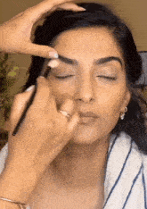a woman with her eyes closed is getting her eyebrows done