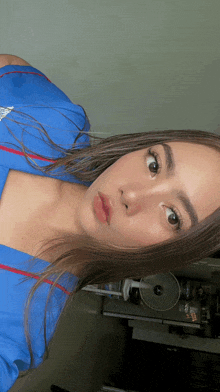 a woman in a blue shirt is taking a selfie in front of a fan