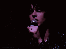 a close up of a person singing into a microphone with juliana.asblancaz written on the bottom
