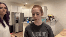 a woman wearing a thrown t-shirt stands next to another woman