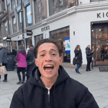 a man with his mouth open in front of a store called kicks
